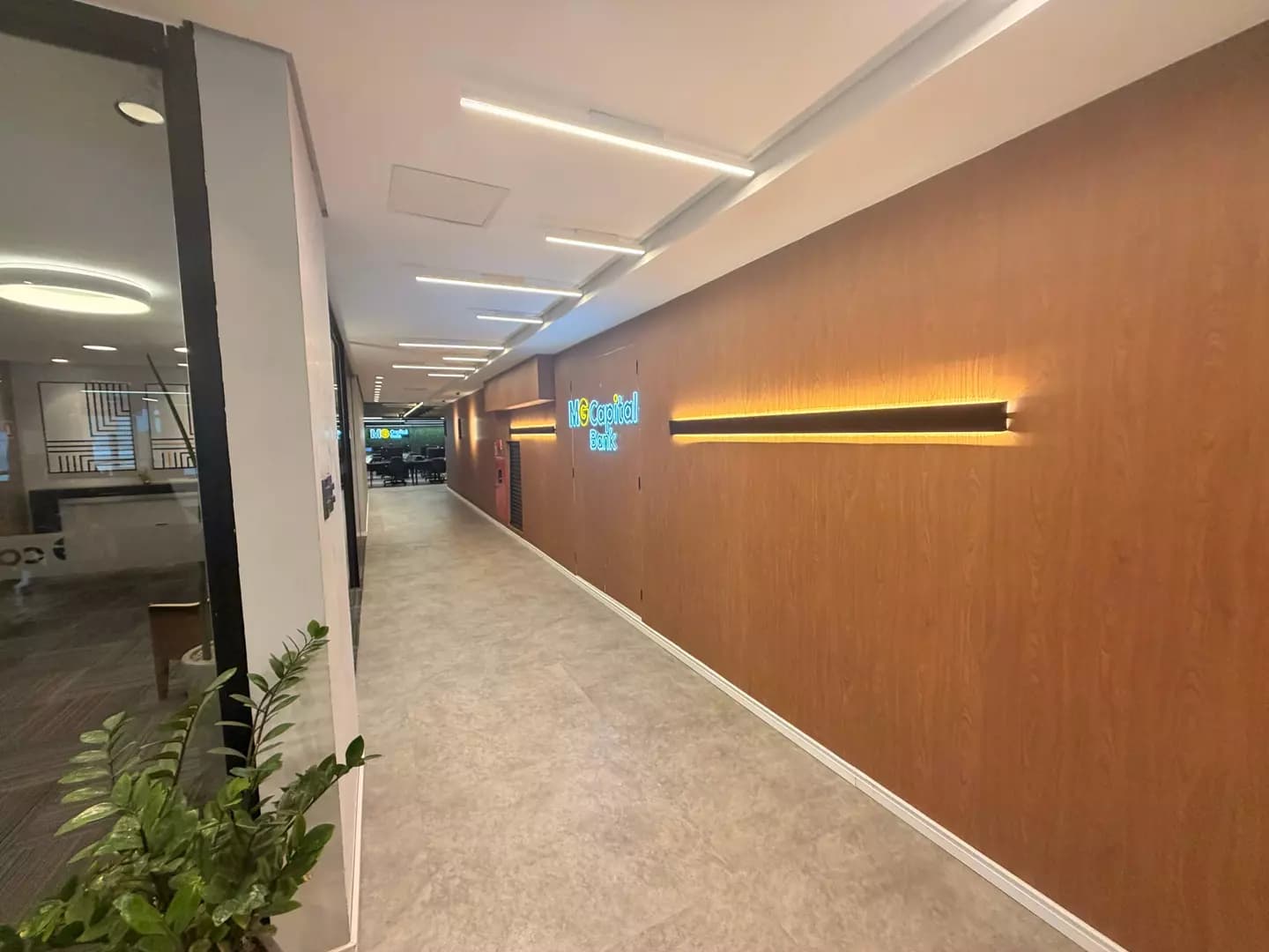 Corredor de madeira com o logo da MG Capital iluminado