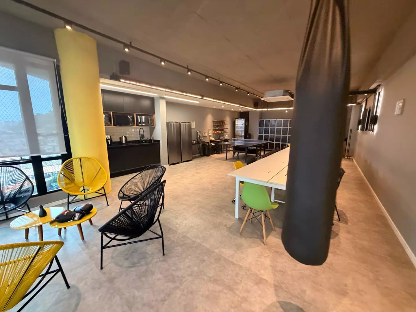 Área de descompressão com poltronas amarelas e mesa de jogos